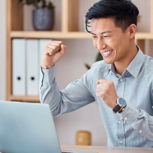 A man celebrates as he reads something on his laptop - square image